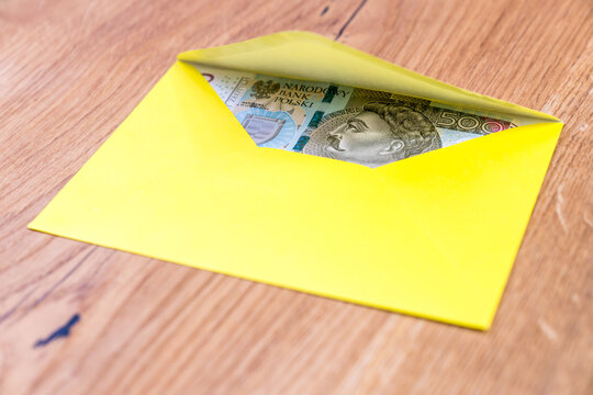 Polish banknotes in yellow envelope on wooden background