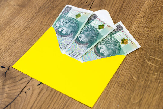 Polish banknotes in yellow envelope on wooden background