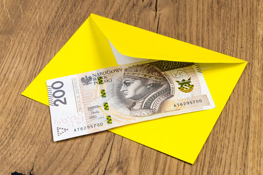Polish banknotes in yellow envelope on wooden background