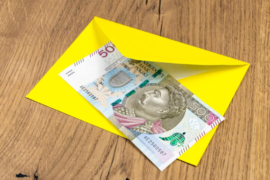Polish banknotes in yellow envelope on wooden background