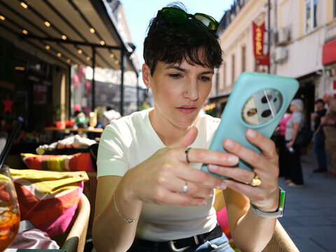 Woman using smartphone at cafe terrace in Bucharest