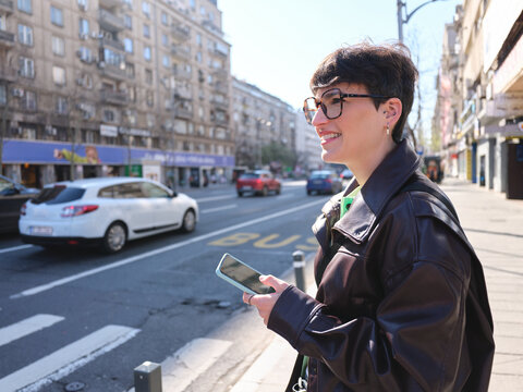 Young woman smiling using smartphone in Bucharest city street