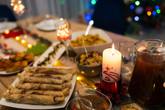 A close-up of a Christmas Eve dinner table in Poland featuring traditional dishes like krokiety, beetroot soup, and kutia under warm candlelight.