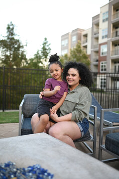 Mother holding smiling toddler son while sitting outdoors.