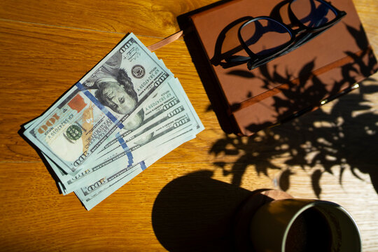 Money and notebook on wooden table with glasses
