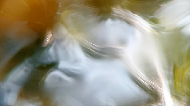 Mesmerizing dance of light and shadow on water surface creates an abstract visual symphony of nature's elements.