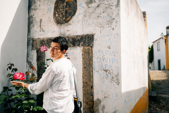 Woman Stands by Wall Holding Flowers in Obidos Street