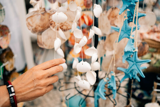 Hand Reaches for Shells at a Market in Coastal Town