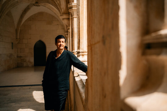 Person Stands by Stone Wall in Historic Building During Daytime