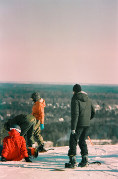Snowboarders prepare to descend down a snowy mountain.
