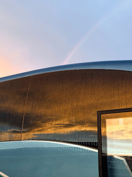 Sunset rainbow reflection on wet bus