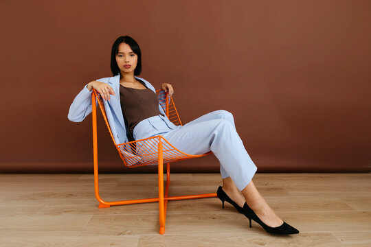 Woman in suit sitting on orange chair