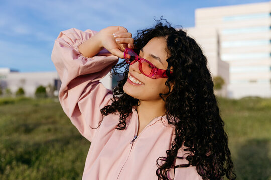 Woman in pink sunglasses smiling outdoors
