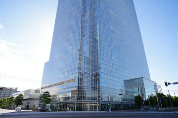 Obraz premium Glass office building exterior with blue sky and sun reflecting on facade