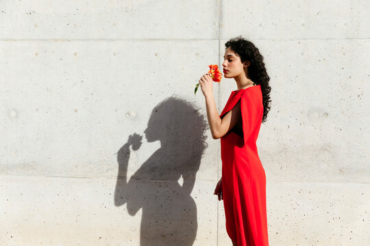 Woman in red dress smelling flower