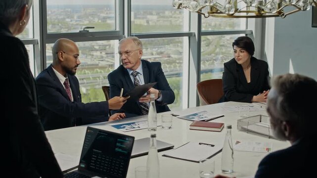 Wide shot of business partners analyzing data and signing contract during corporate board meeting in modern office. Ideal for B2B marketing, financial services, and corporate communication videos