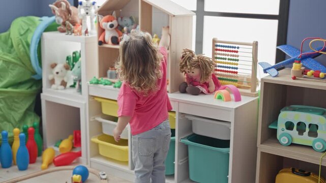 Girl standing with hand on hip facing a toy shelf with doll and abacus in a bright playroom inside a building; playfulness curiosity.