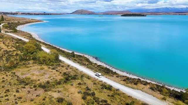 Aerial drone view of a 4x4 camper driving near Lake Tekapo, New Zealand. The breathtaking beauty of the South Island. An idyllic road trip.	
