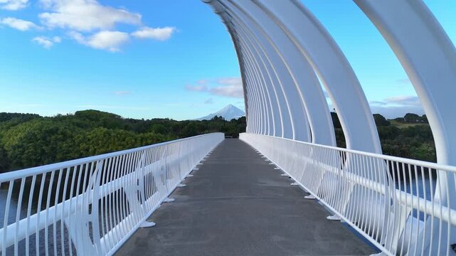 Aerial drone view of Mount Taranaki. Te Rewa Rewa Bridge pedestrian bridge and cycling path across the river. New Plymouth, New Zealand.