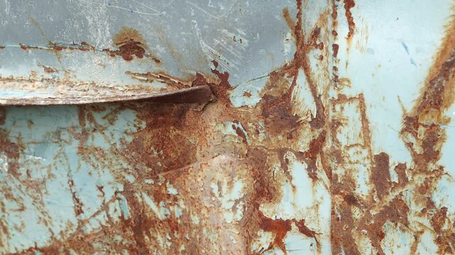 Close-up of weathered rusty painted steel surface with peeling paint and corrosion texture