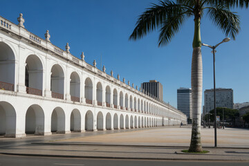 Fototapeta premium Historic white building with arched colonnade and palm tree, architecture
