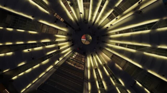 Aerial view of a modern circular atrium with radial lights and people walking on multiple levels in a symmetrical architectural design in Tirane, Tirana County, Albania.