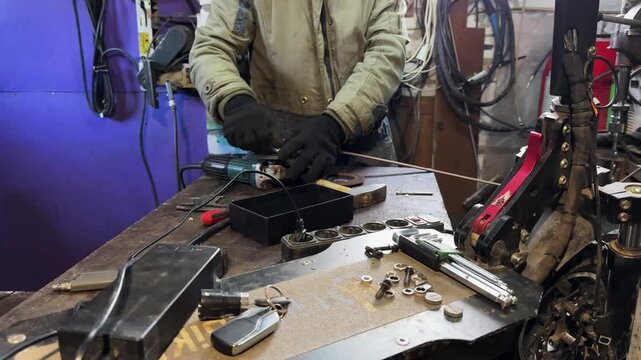 Arms of professional repairman prepare circular saw to grinding metal detail. Male hands in protective gloves of mechanic ready to using electric grinder wheel at workplace. Slow motion