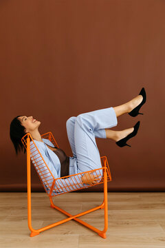 Stylish woman having fun in orange chair