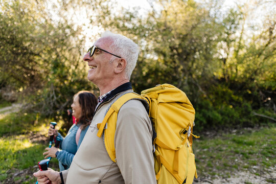 Senior man smiling hiking with backpack in nature