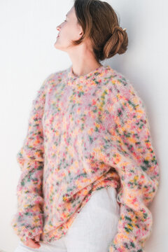 Woman in Colorful Sweater Leans Against Wall Indoors