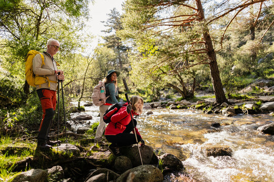 Three hikers exploring forest river during outdoor adventure