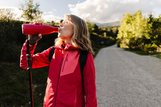 Senior woman hydrating during her walking adventure outdoors