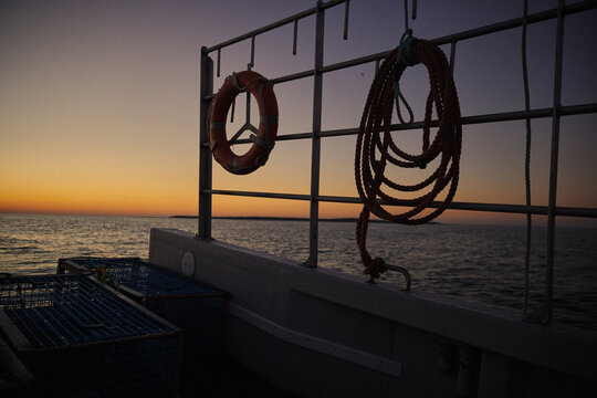Sunset view from a boat on water with ropes and safety ring