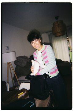 Happy woman packing backpack with belongings indoors