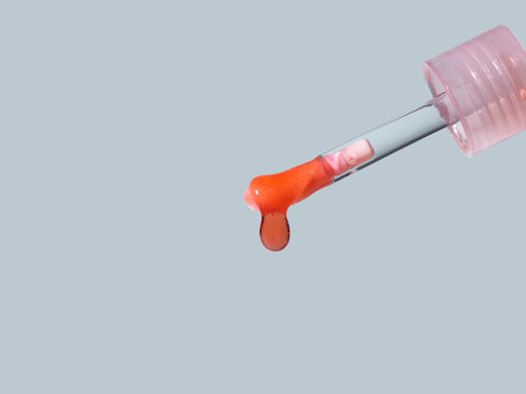 Close-up of a dropper dispensing a vibrant orange liquid