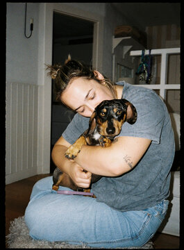 Young woman cuddling a dachshund puppy, expressing affection and bond