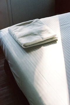 Sunlit Towel Neatly Placed on Tidily Made Bed