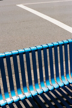 Blue metallic bench casting long shadows outdoors