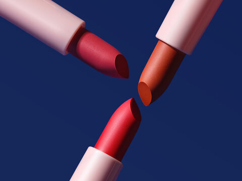 Three lipsticks in different shades against a vibrant blue background.