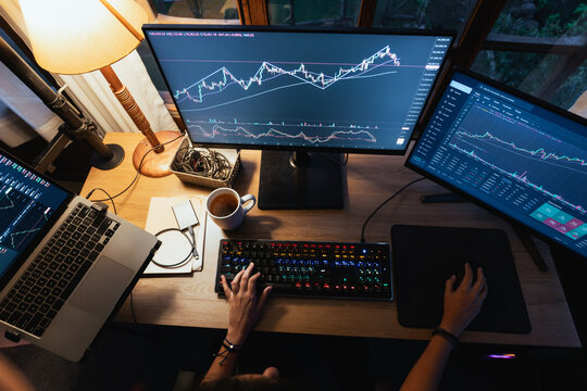 Trader hands working with Stock chart on Multiple Screens