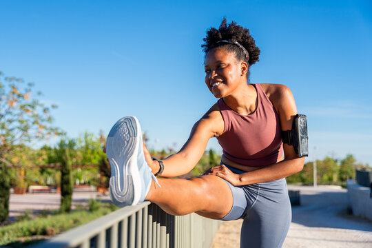African american woman stretching leg before running workout