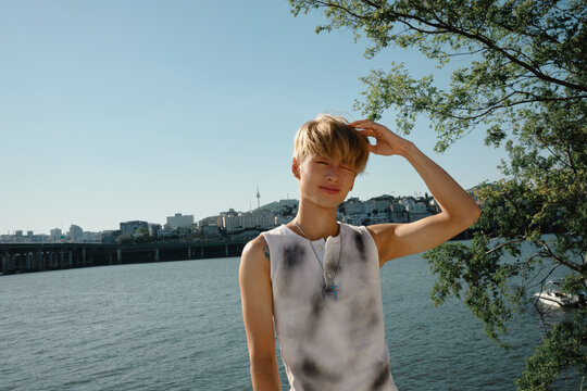 Young man posing by Hangang River with Seoul skyline backdrop