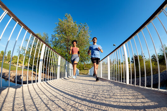 Multiethnic couple running on a bridge in a park