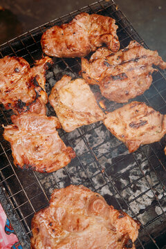 Street vendor grills chicken in a busy market in the afternoon