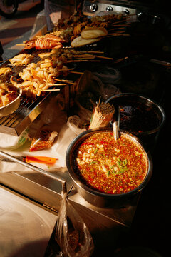 Street food scene with skewers and spicy sauce in the evening