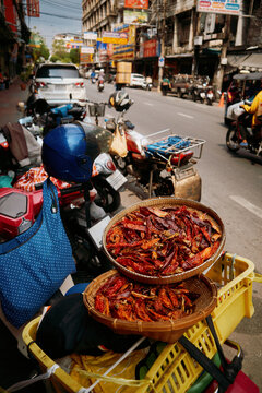 Drying red chilies on a street in a busy market area during the day