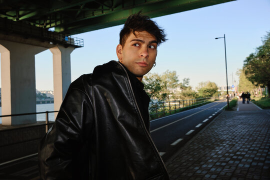 Young man in leather jacket standing beneath bridge in Seoul