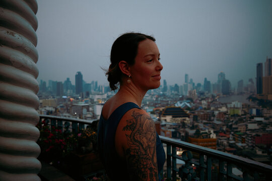 Person looks at city skyline during cloudy evening in urban area