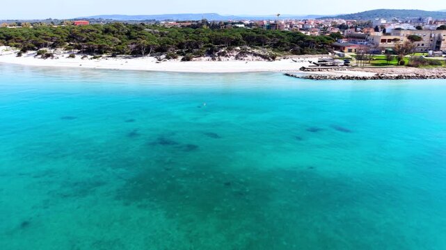 Loopable aerial view of Maria Pia Beach seen from the sea showing turquoise water sandy coastline and Mediterranean shore in smooth cinematic motion.