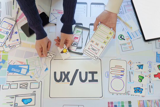 Overhead view of designers brainstorming mobile app interface with paper prototypes